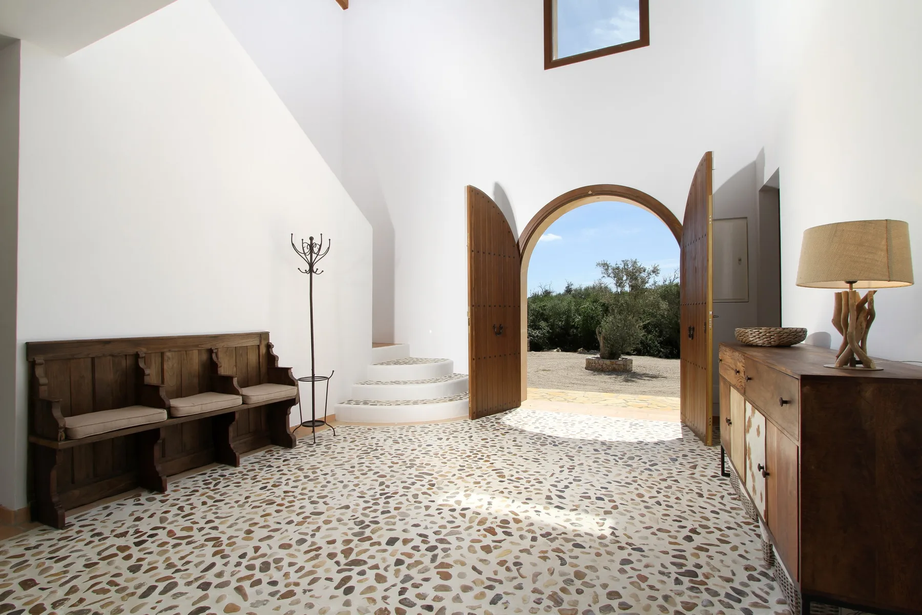 A bright entry hall with an arched doorway opening onto greenery.