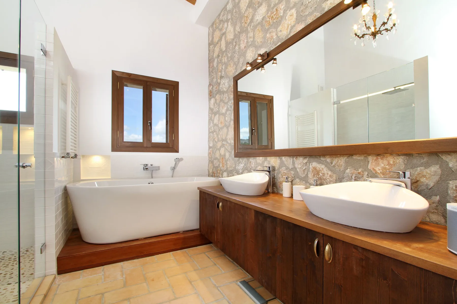 A bathroom with a bathtub and a long vanity topped with two vessel sinks.
