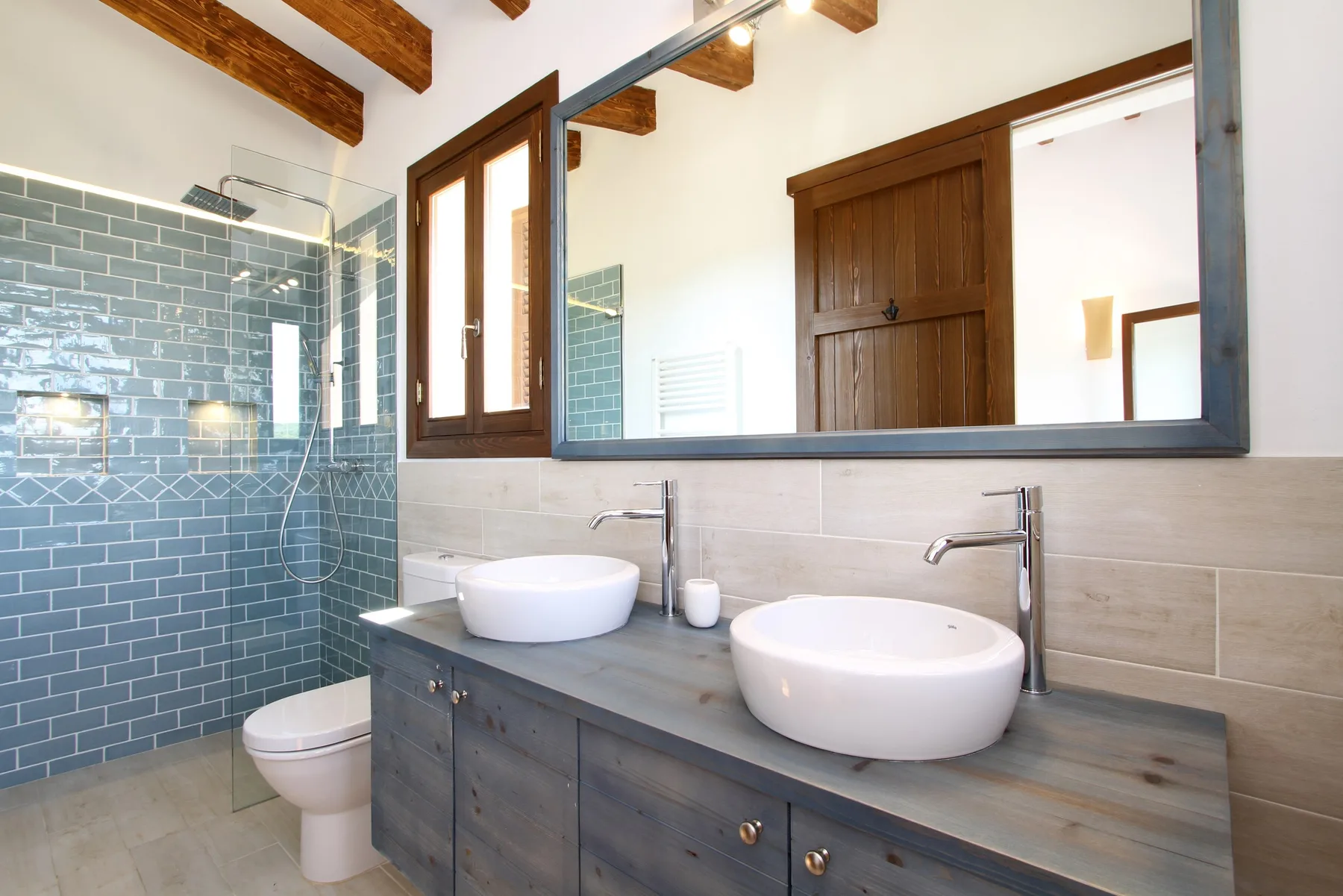 A bathroom with two sinks, a large mirror, and a tiled shower.
