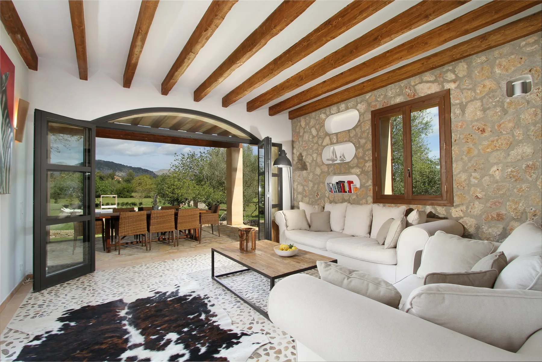 A bright living room with white seating and an open doorway to a dining terrace.