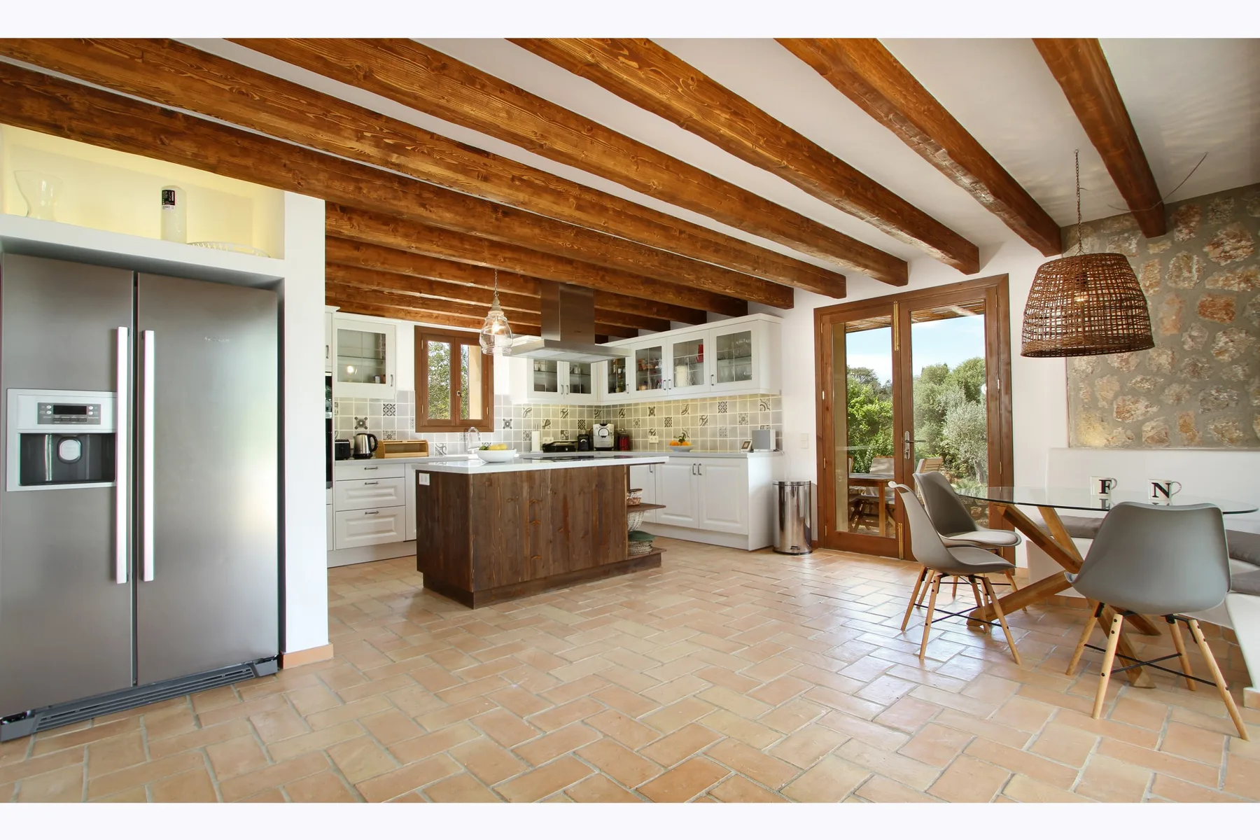 A bright open-plan kitchen and dining area with exposed wooden ceiling beams.