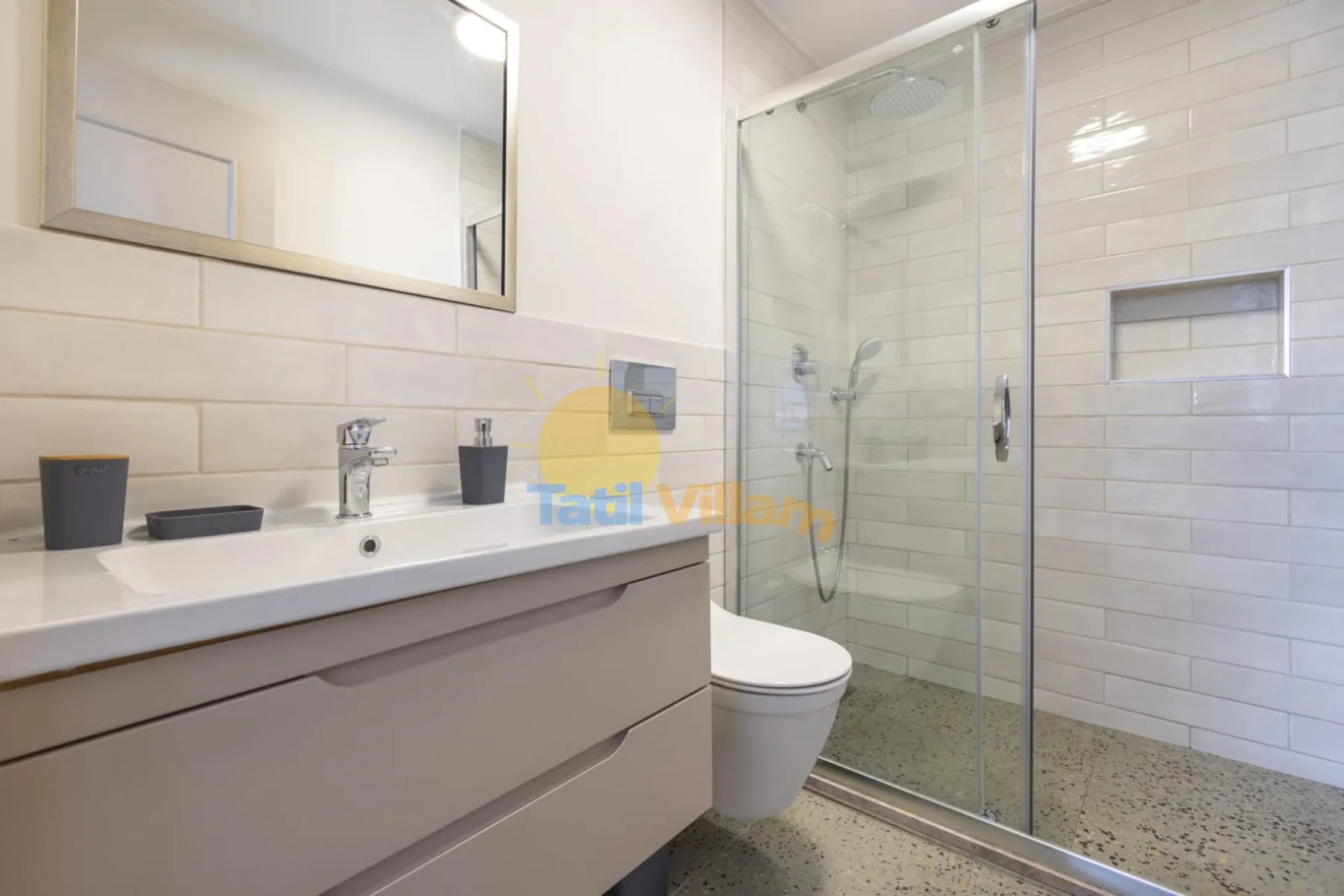 A modern bathroom with a vanity, toilet, and glass-enclosed shower.