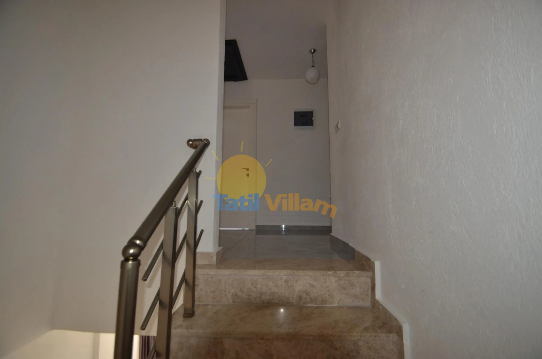 Una estrecha escalera interior con peldaños de piedra y pasamanos metálico.