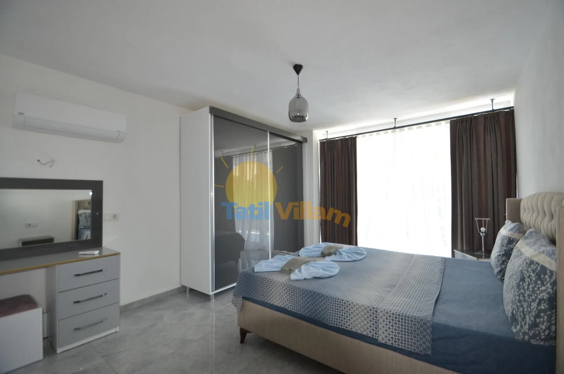 Un dormitorio con una cama junto a una gran ventana con cortinas.