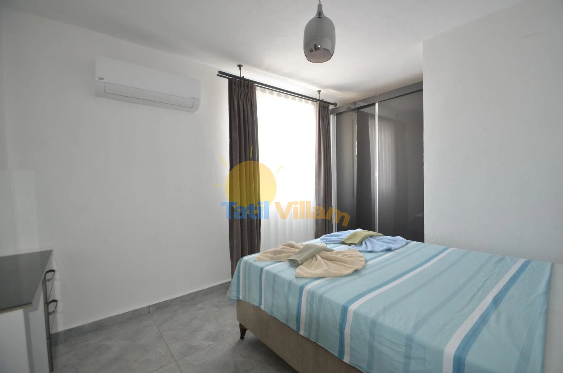 Un dormitorio con una cama de ropa de cama azul a rayas junto a una ventana luminosa.