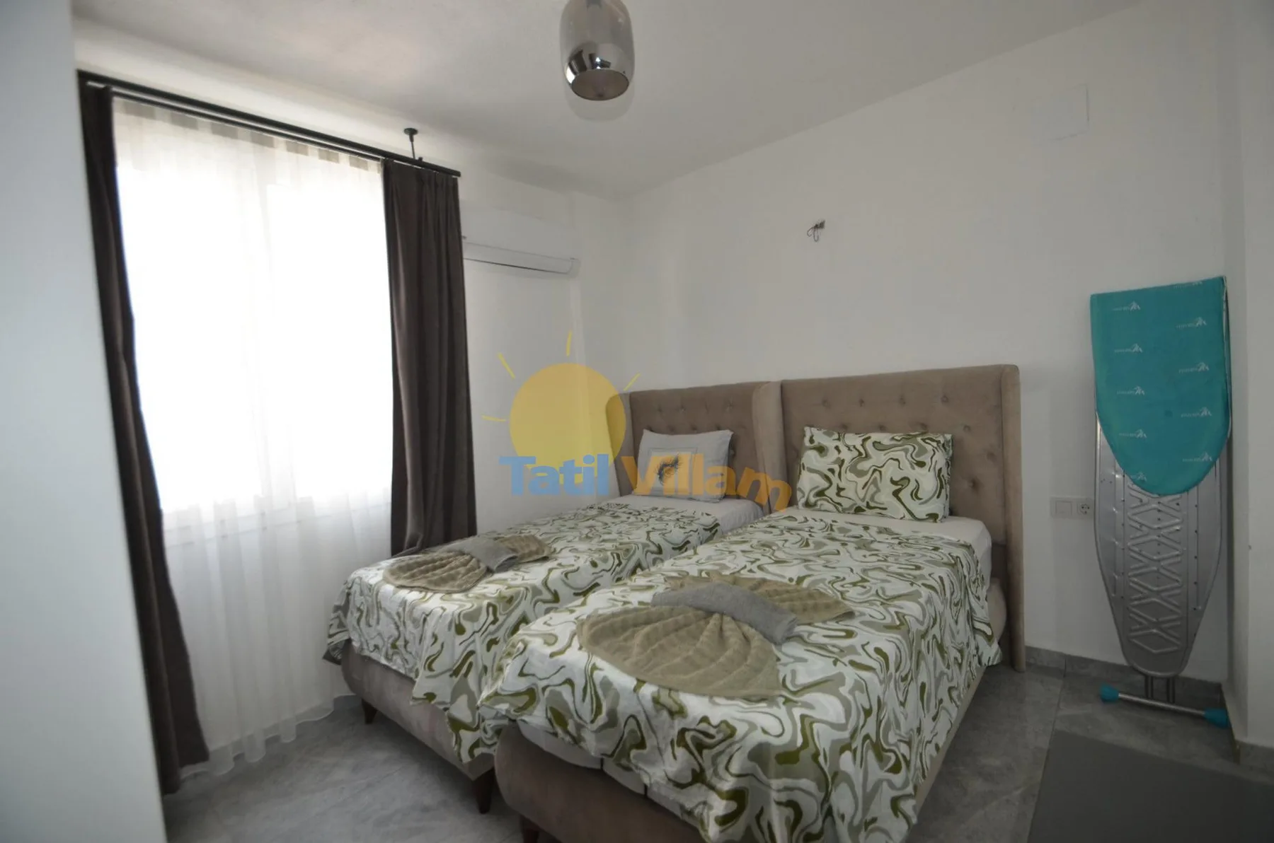 Un dormitorio con una cama doble cubierta con ropa de cama estampada junto a una ventana con cortinas.
