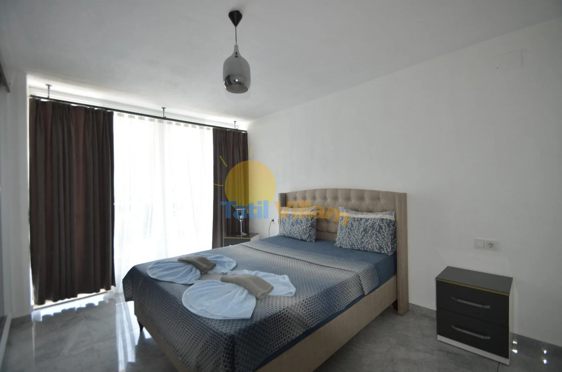 Un dormitorio con una cama junto a una gran ventana con cortinas.