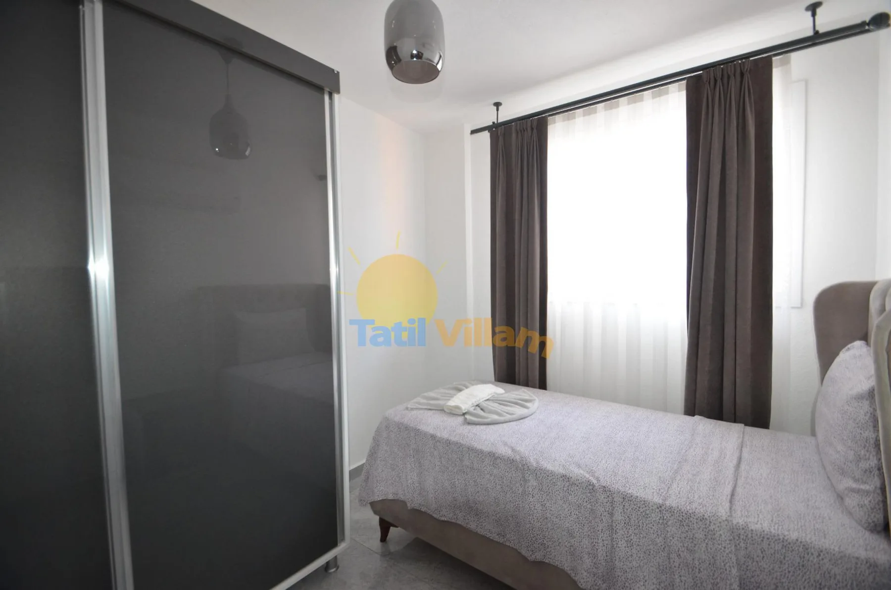 Un dormitorio con una cama junto a una ventana grande con cortinas.