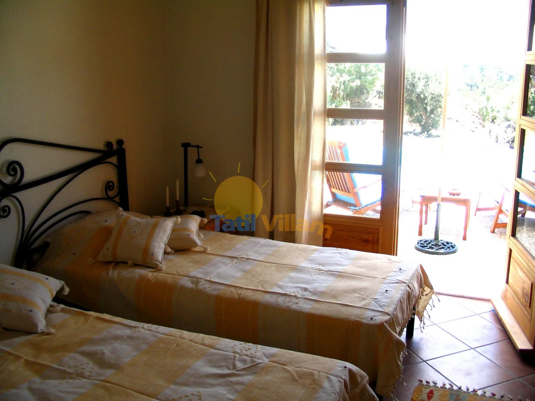 Un dormitorio con dos camas junto a una puerta de cristal luminosa que da a un patio.