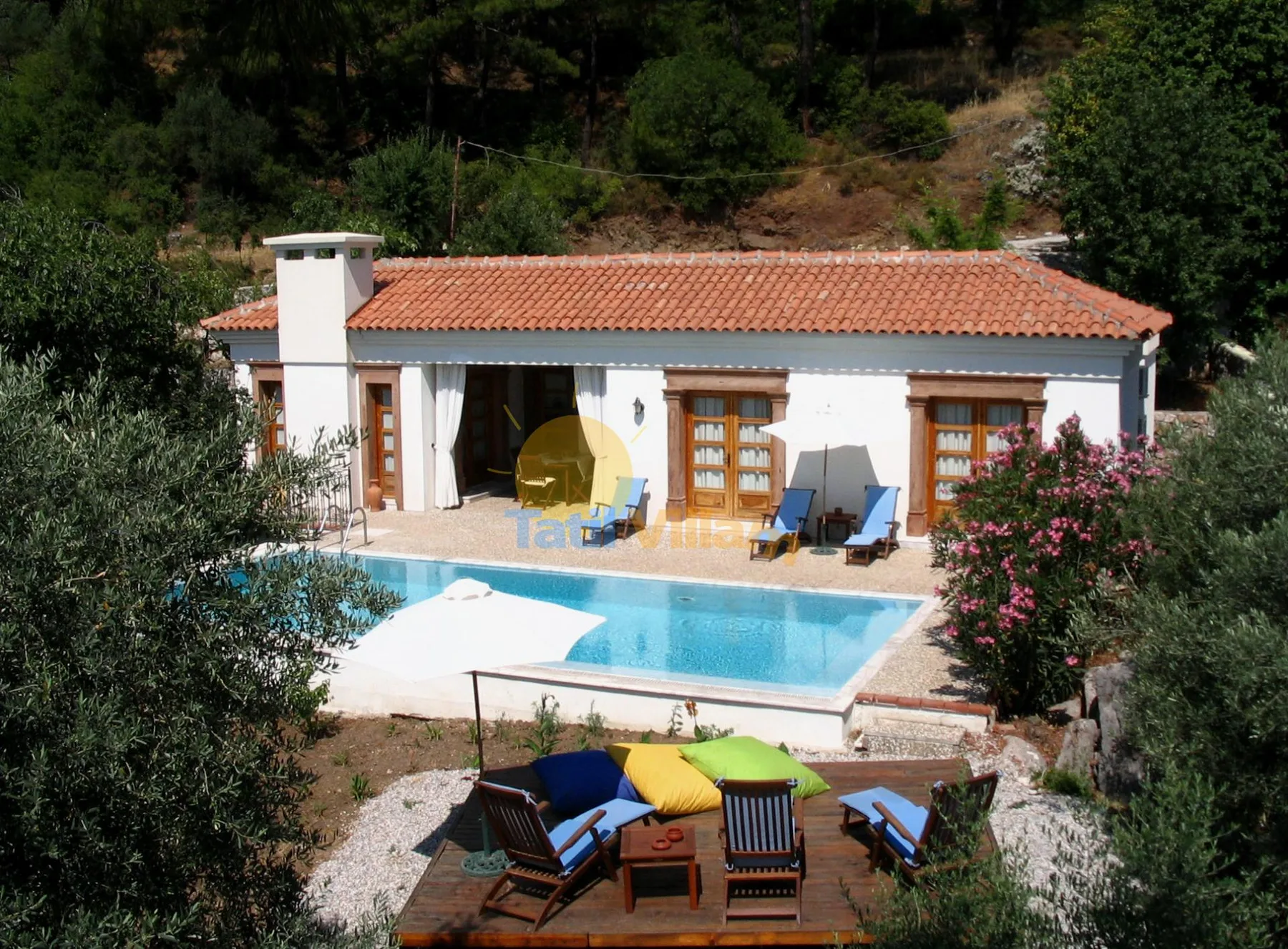 Una casa blanca con techo de tejas terracota da a una piscina y una zona de estar al aire libre.