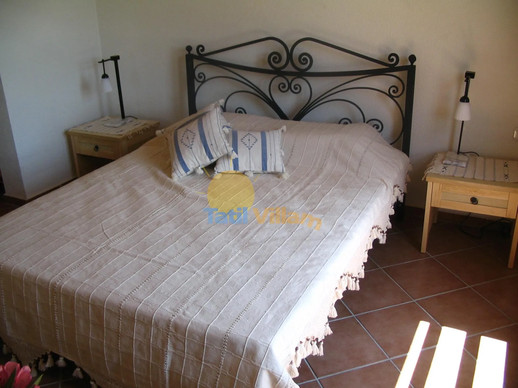 Un dormitorio con una cama, almohadas estampadas y mesitas de noche a juego.