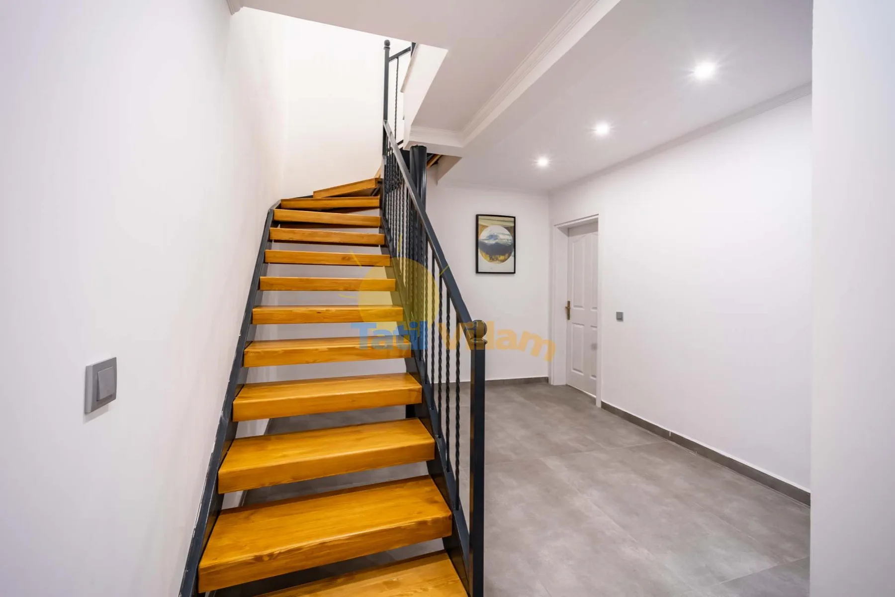 A bright interior stairway with wooden steps and dark metal railings.