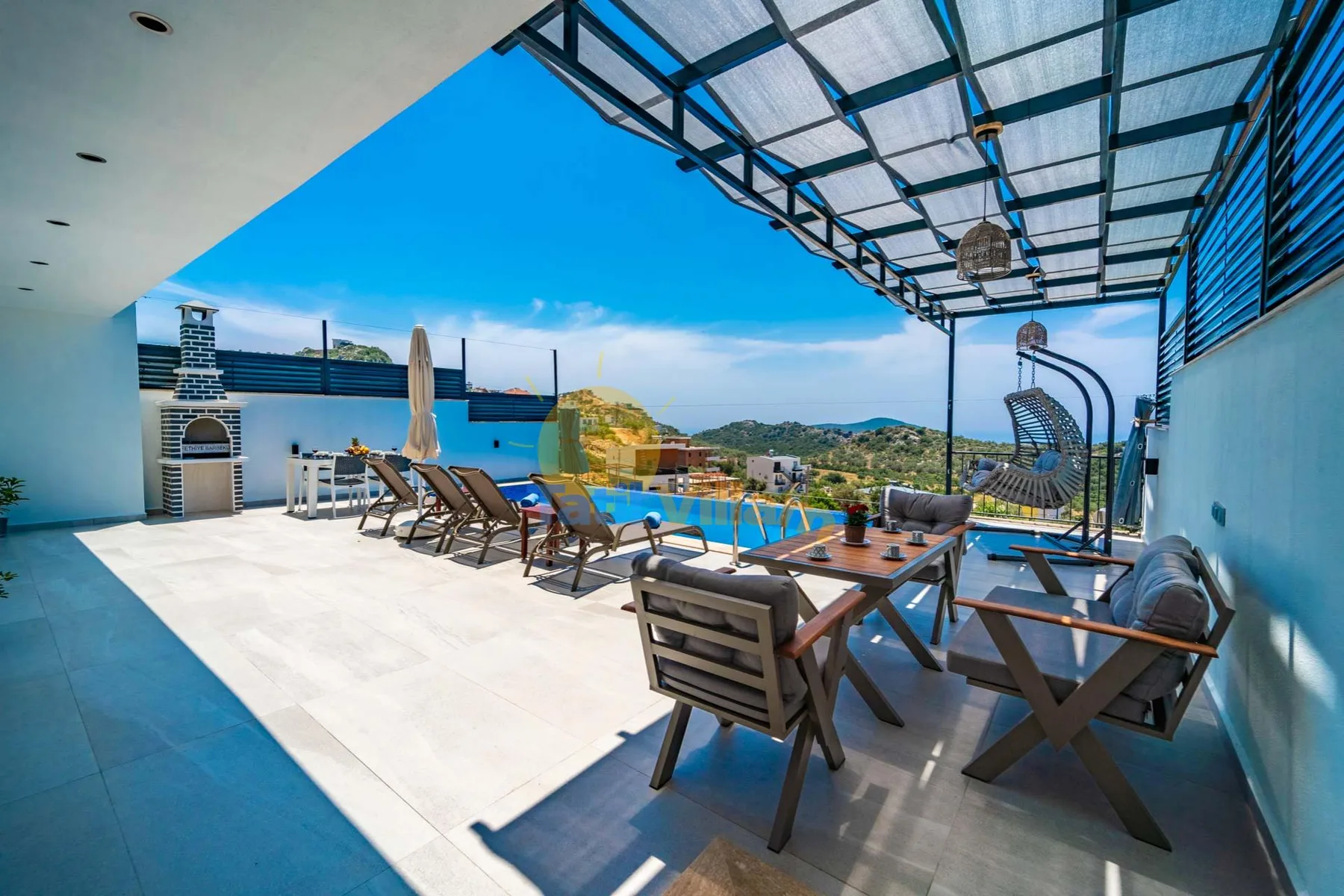 An open-air terrace has dining seating beneath a translucent roof, overlooking a hillside.