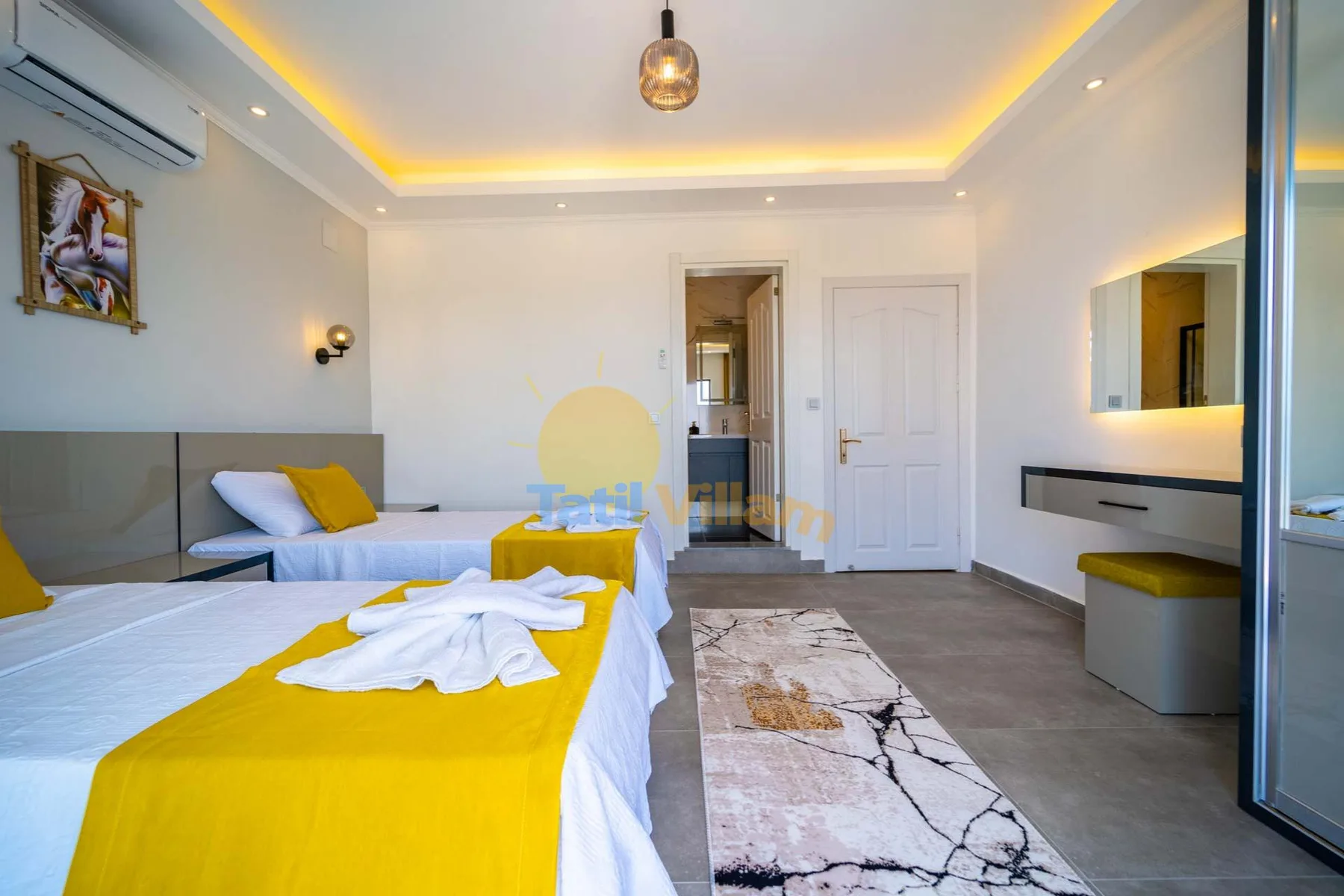 A bedroom with two beds, yellow bedding, and a desk.