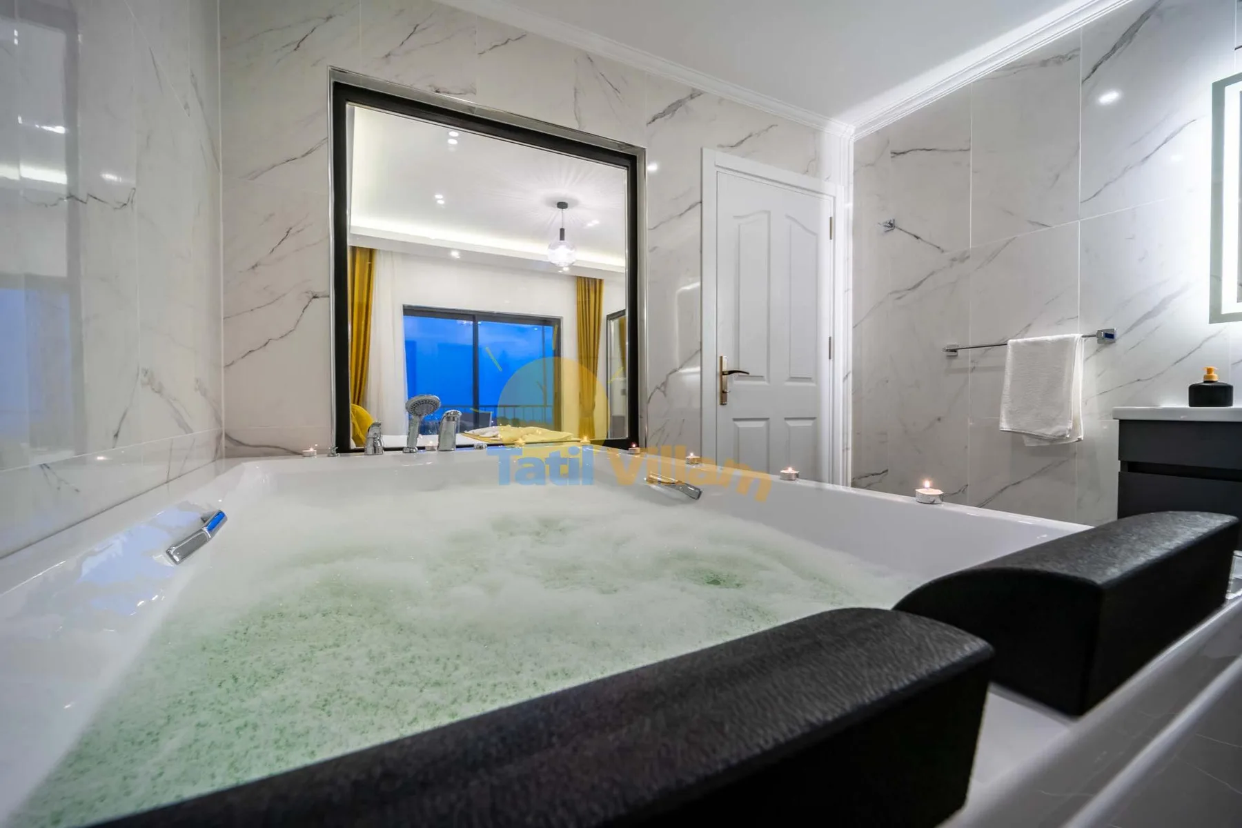 A marble-tiled bathroom with a bathtub filled with foamy water.