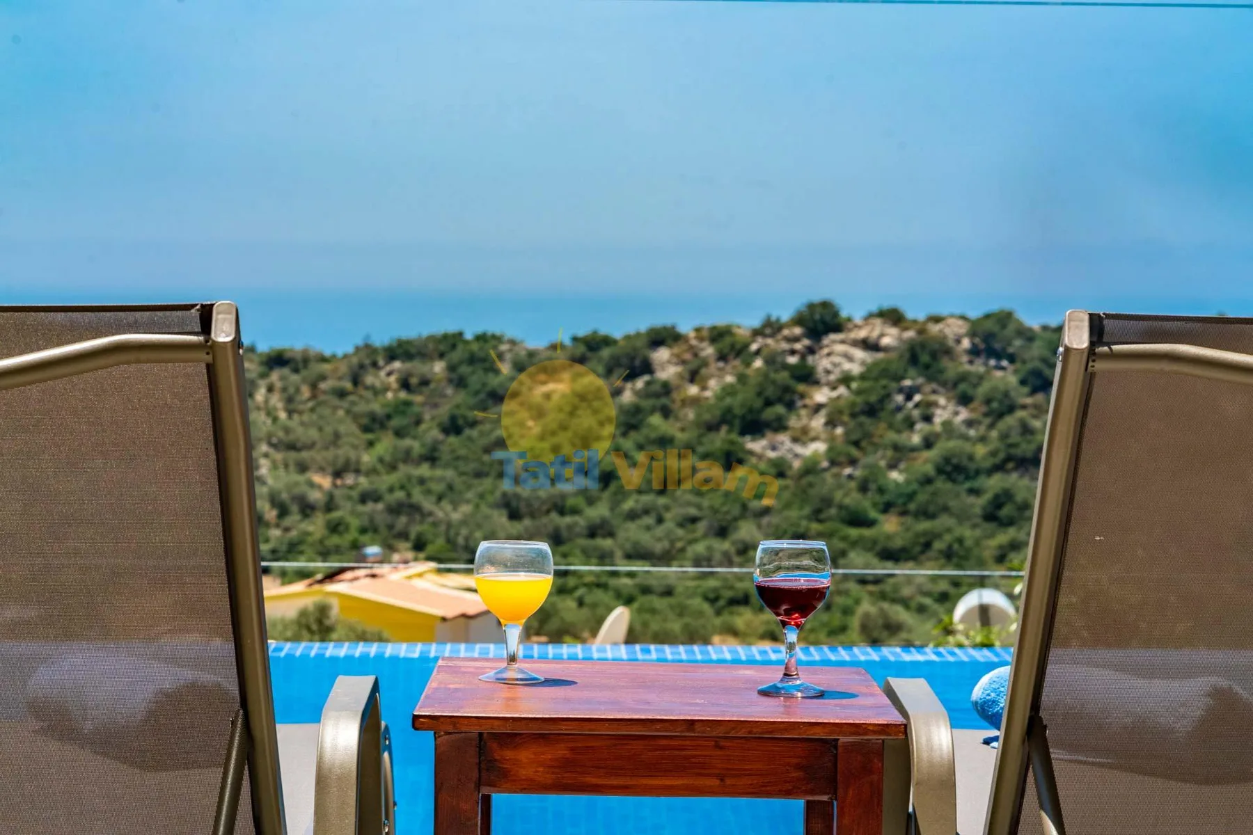 Outdoor seating overlooks a swimming pool and a green hillside.
