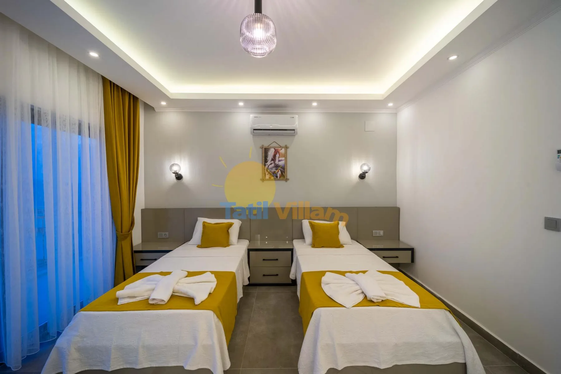 A bedroom with two beds and yellow bedding beneath recessed ceiling lights.