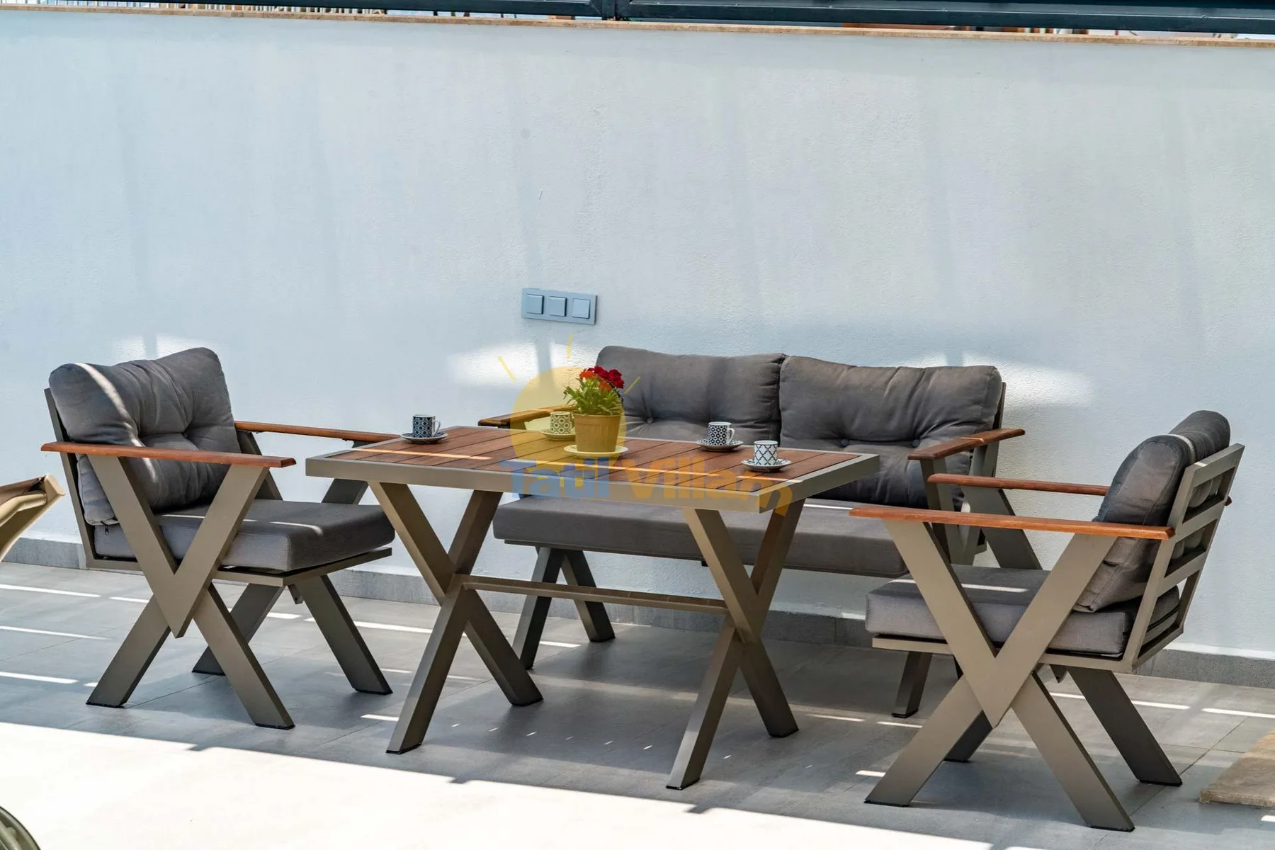 An outdoor seating area with a table and cushioned chairs.