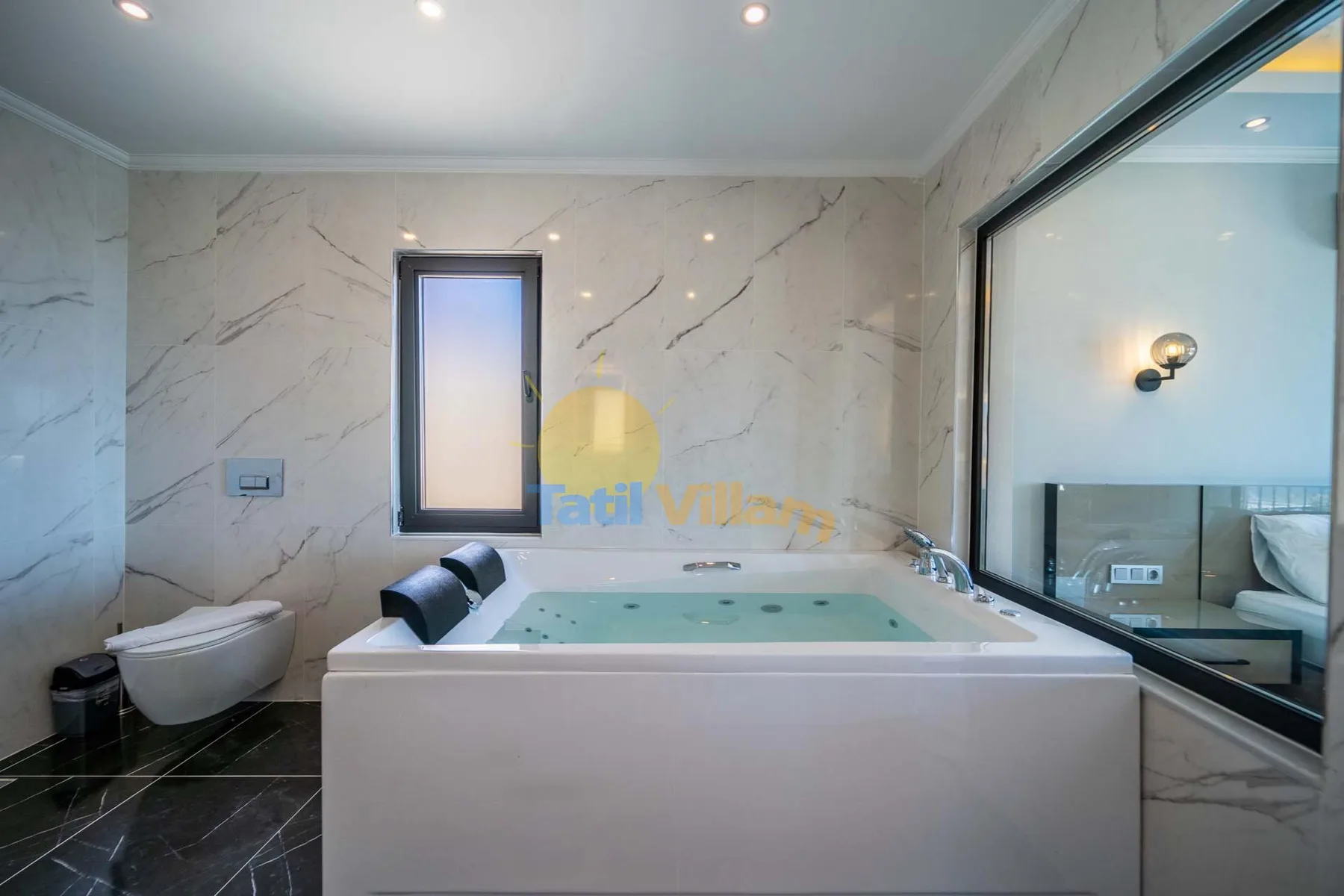 A bathroom with a large rectangular soaking tub and marble-patterned walls.