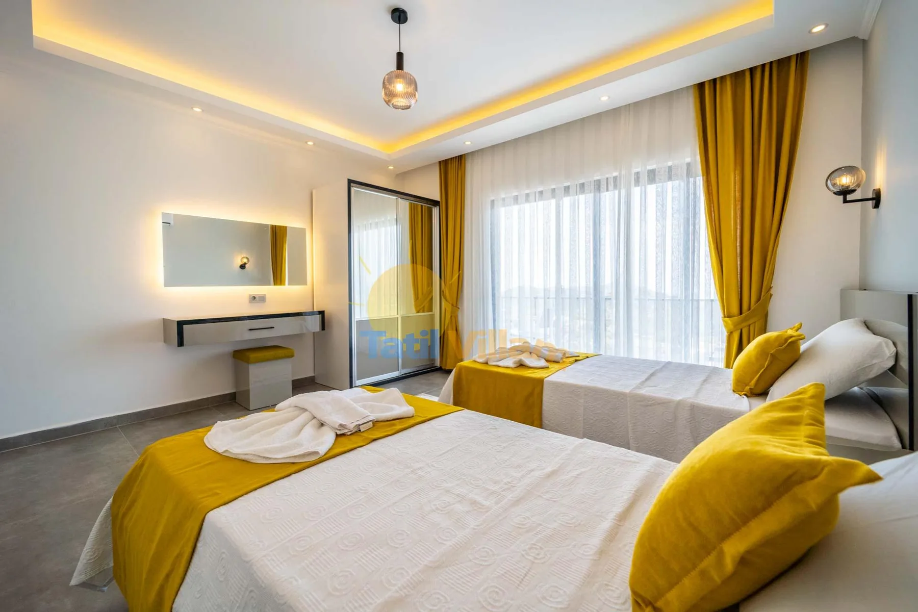 A bright bedroom with two beds dressed in white and yellow linens.