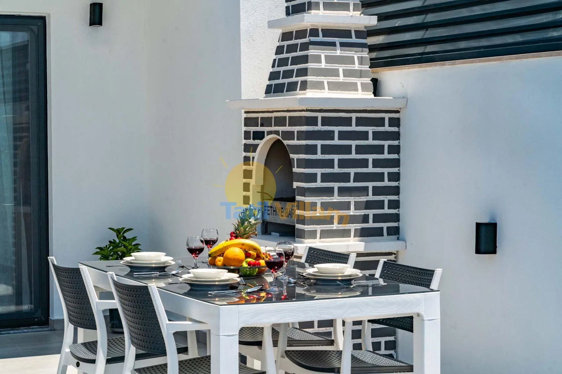 An outdoor dining area with a table set beside a brick barbecue.