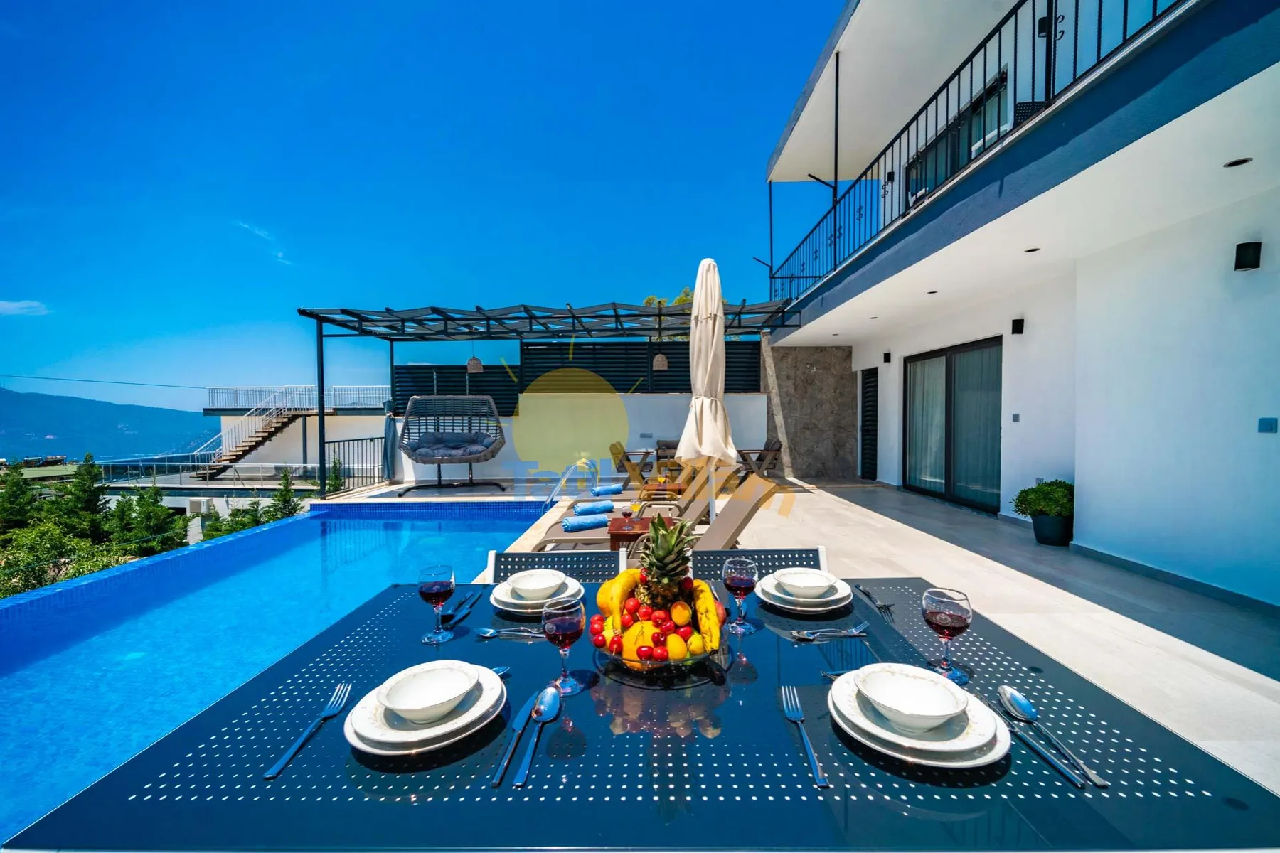 A poolside dining table is set beside a swimming pool at a modern outdoor terrace.