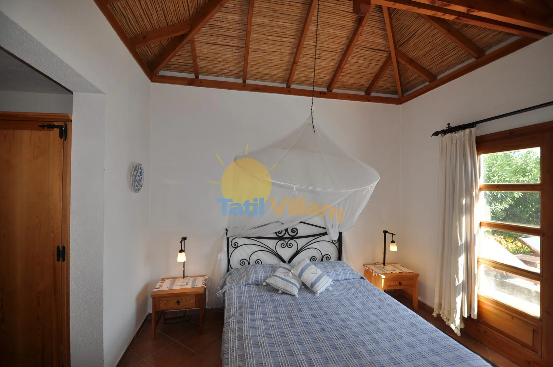 A bedroom with a bed beneath a canopy and a high timber ceiling.