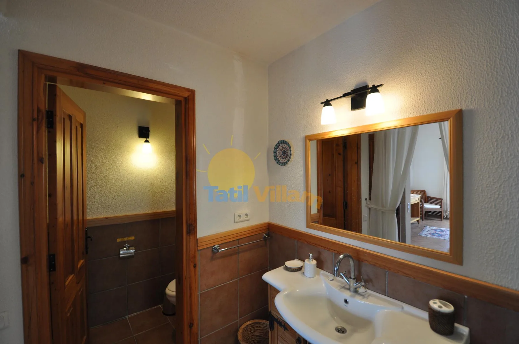 A bathroom with a sink and a large wall mirror beside an open doorway.