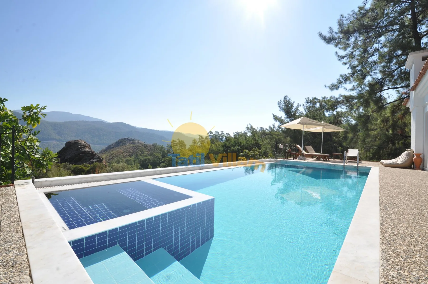 An outdoor swimming pool with blue-tiled steps and mountain views.