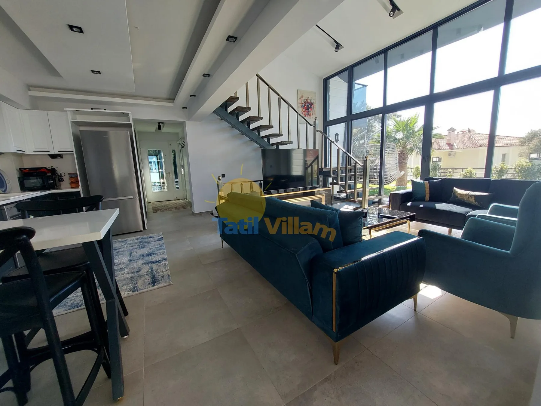 Un salón diáfano y luminoso con cocina, zona de estar y grandes ventanales.