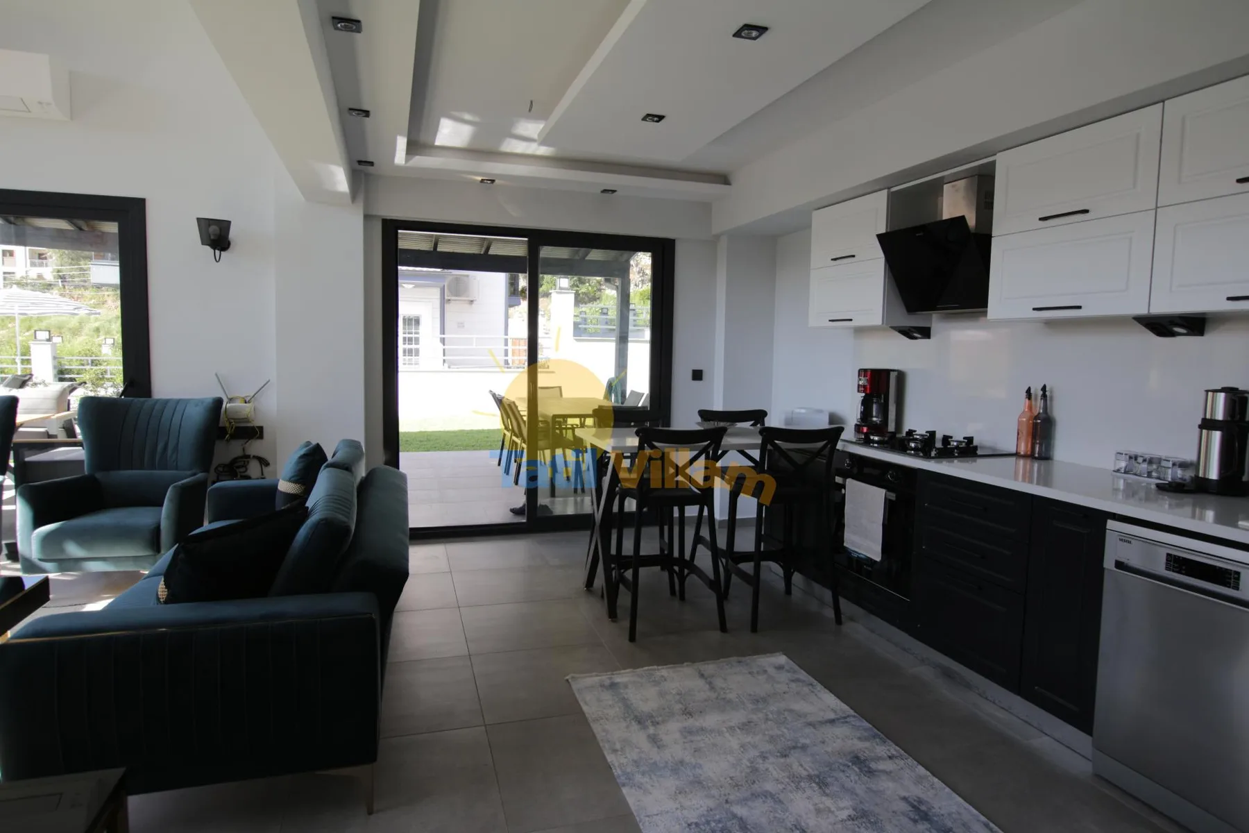 Una cocina abierta al salón tiene una mesa de comedor junto a las puertas corredizas de vidrio.