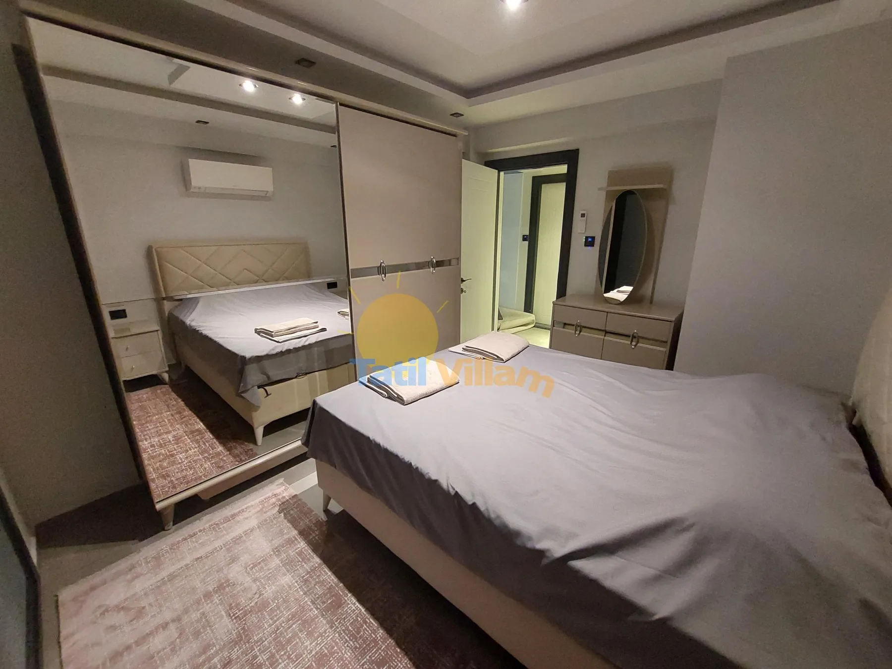 Un dormitorio con una cama grande, un armario con espejo y una puerta a otro espacio.