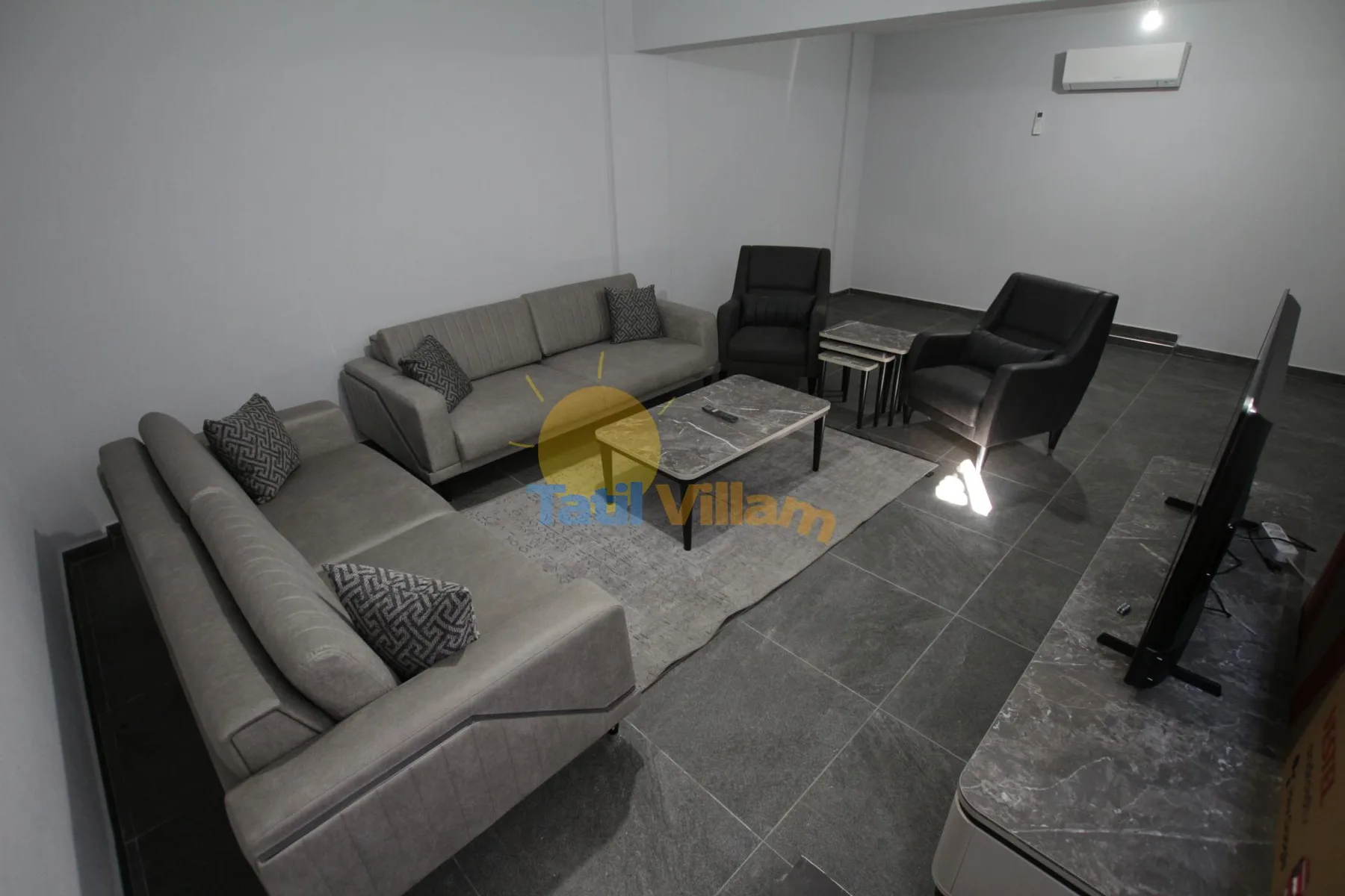 Una sala de estar con asientos alrededor de una mesa de centro sobre una alfombra.