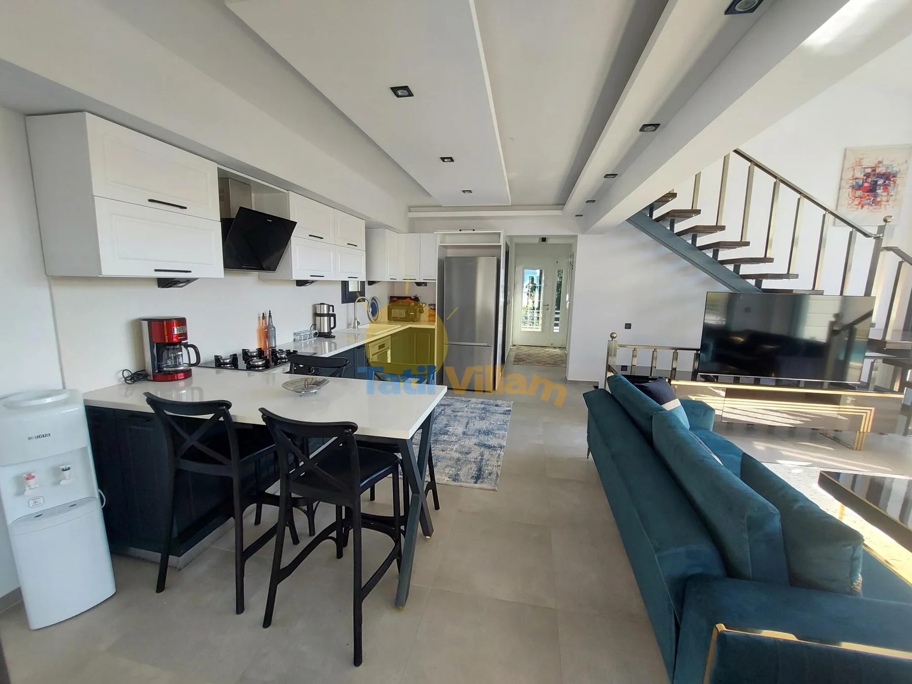Una sala de concepto abierto con cocina, mesa de comedor y asientos azules.