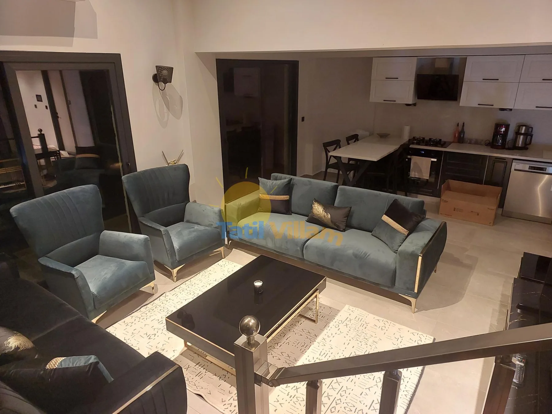 Sala de estar con asientos y mesa de centro, junto a una cocina compacta y un comedor.