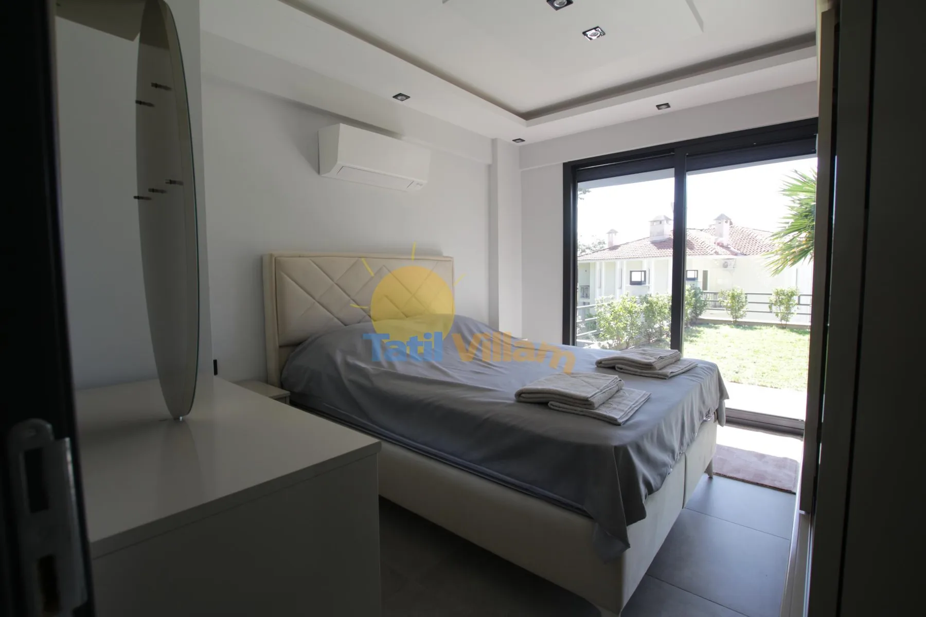 Un dormitorio con una cama junto a grandes puertas corredizas de vidrio que dan a un jardín.
