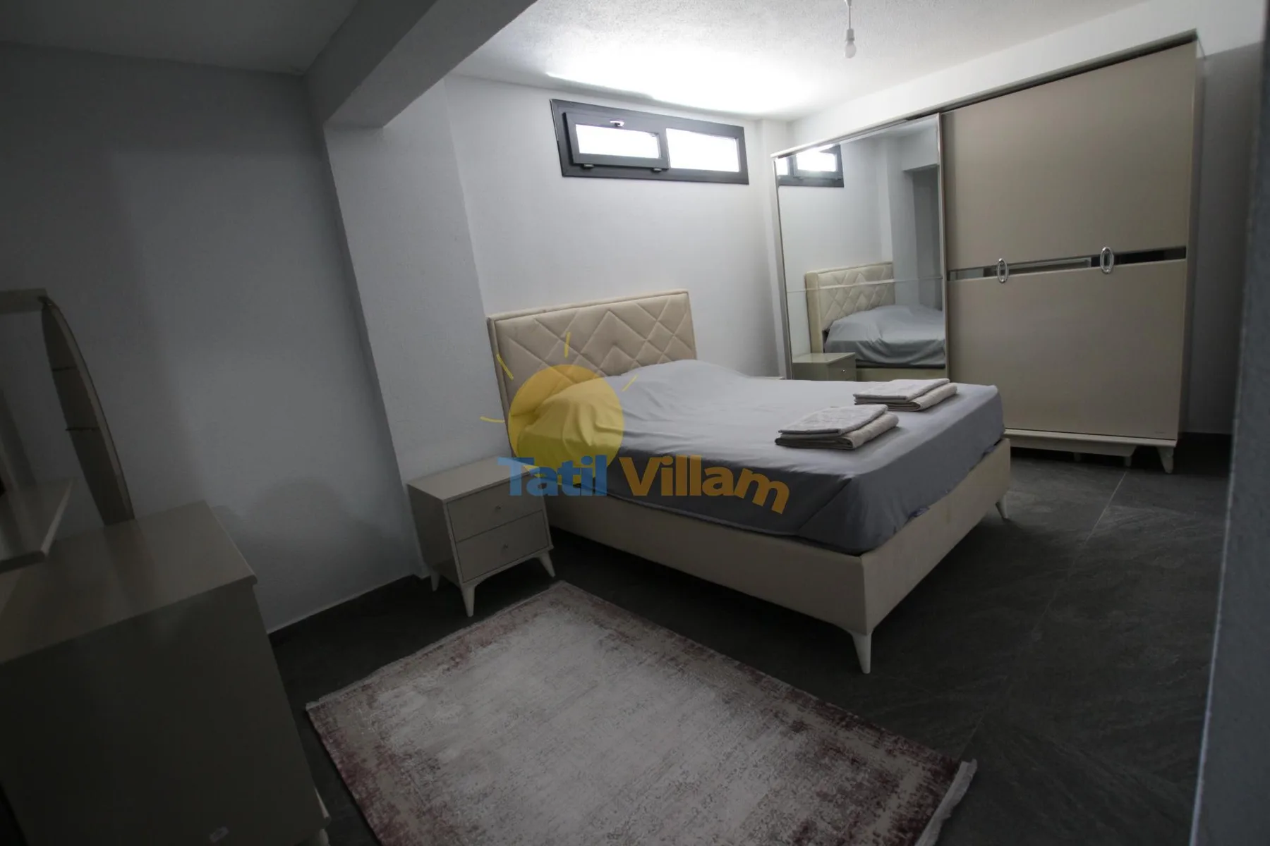 Un dormitorio con una cama, un armario con espejo y una alfombra.
