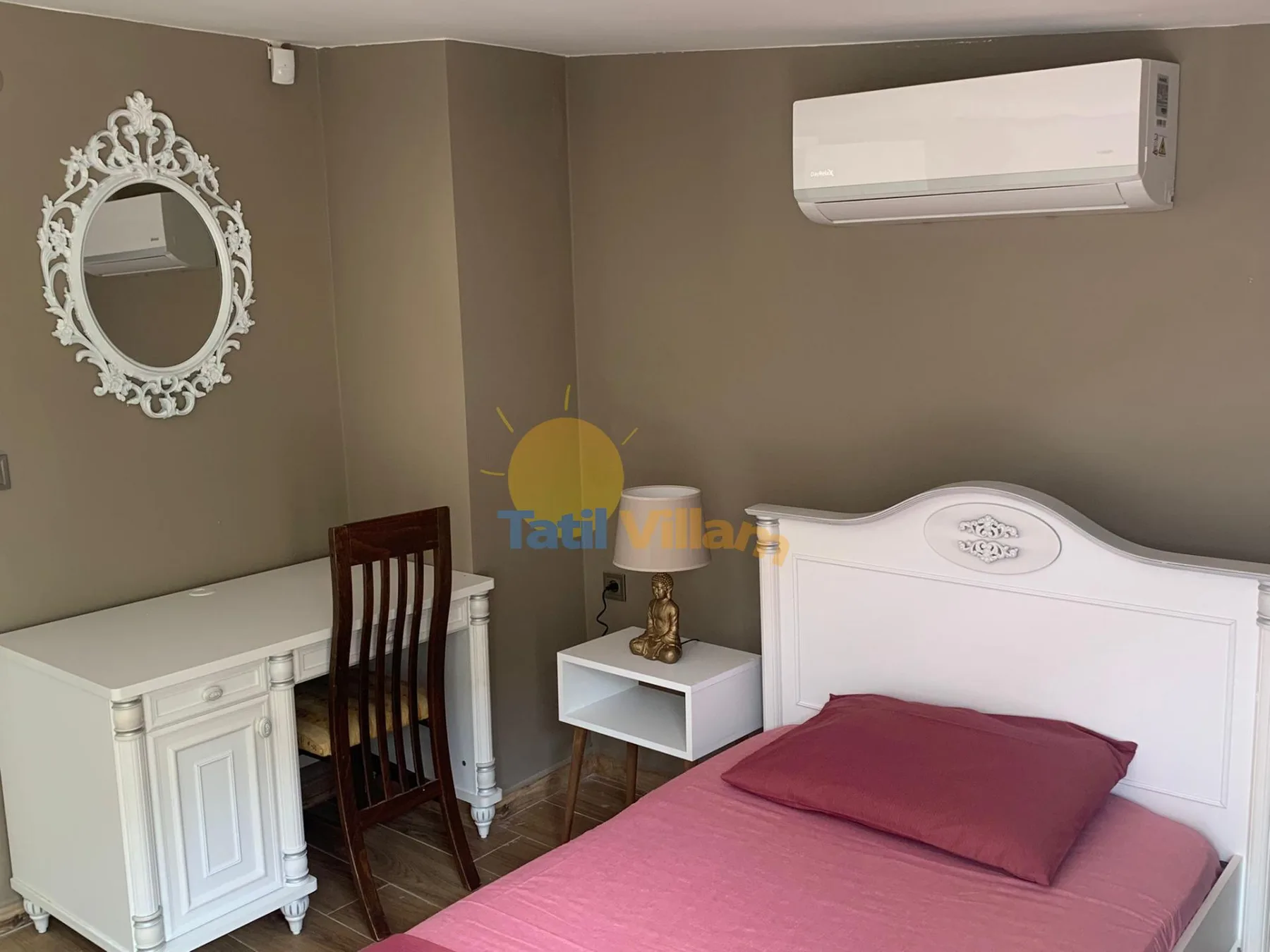 A bedroom with a bed, desk, and wall-mounted air conditioner.
