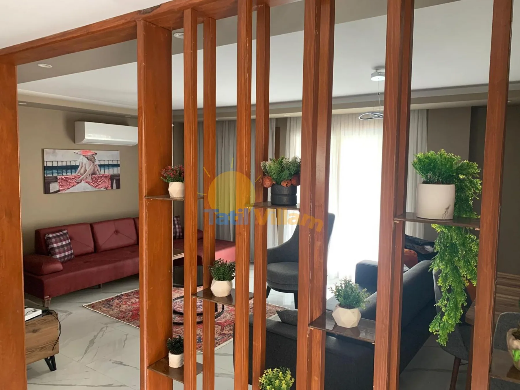 A living room with seating, a rug, and plants behind wooden divider slats.