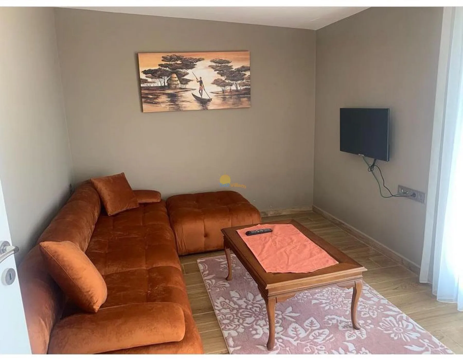 A living room with brown seating and a television mounted on the wall.