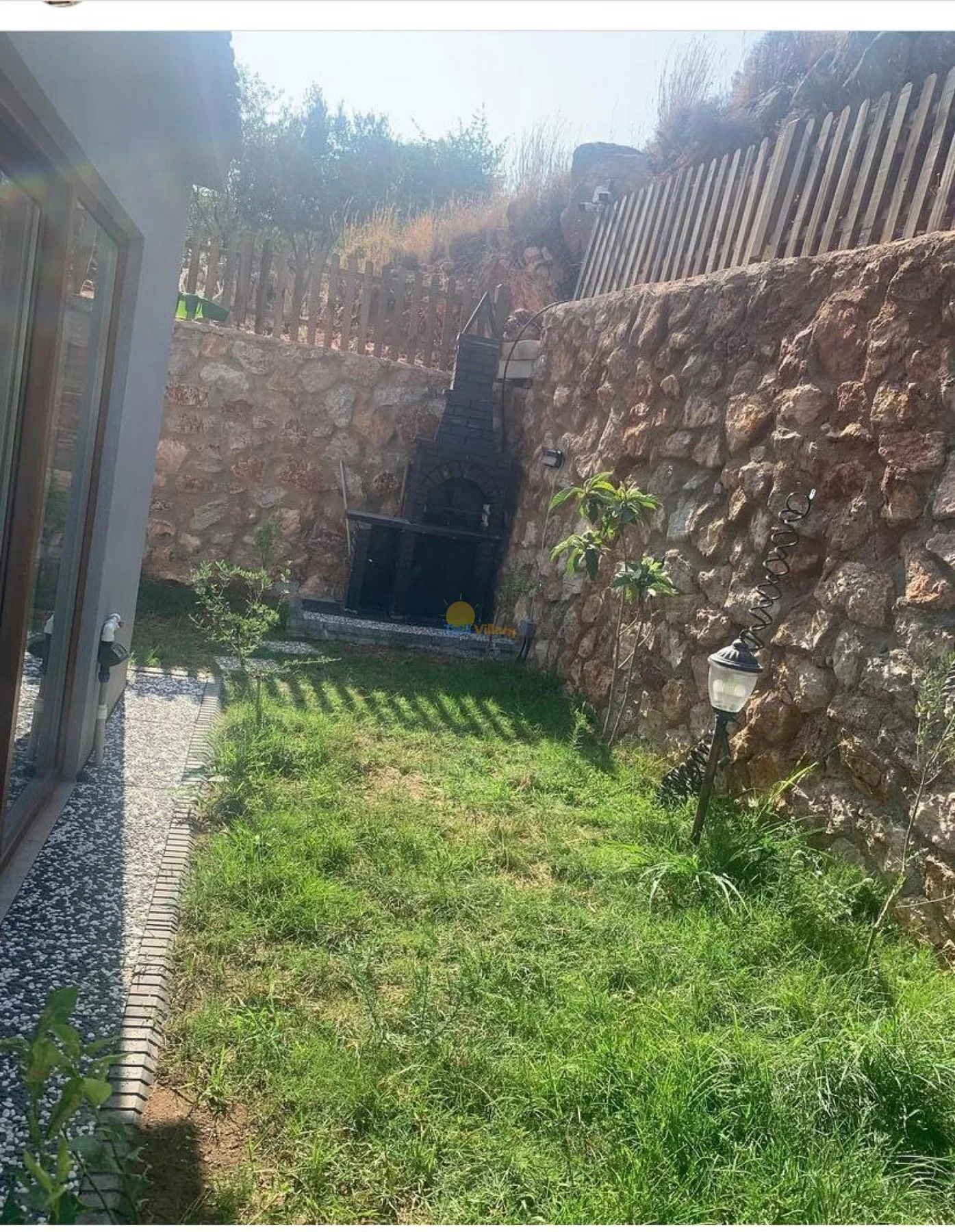 A small grassy courtyard is bordered by stone walls and wooden fencing.