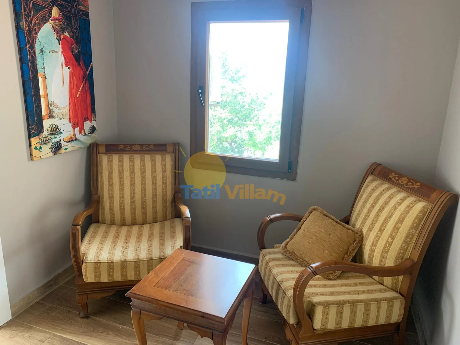 A sitting area with two upholstered seats and a wooden coffee table beside a window.