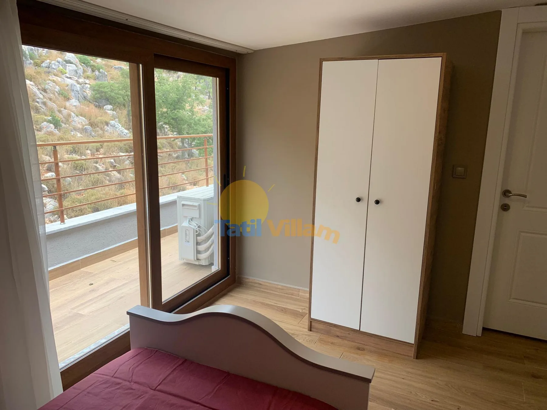 A bedroom with a bed, wardrobe, and large windows overlooking a balcony.