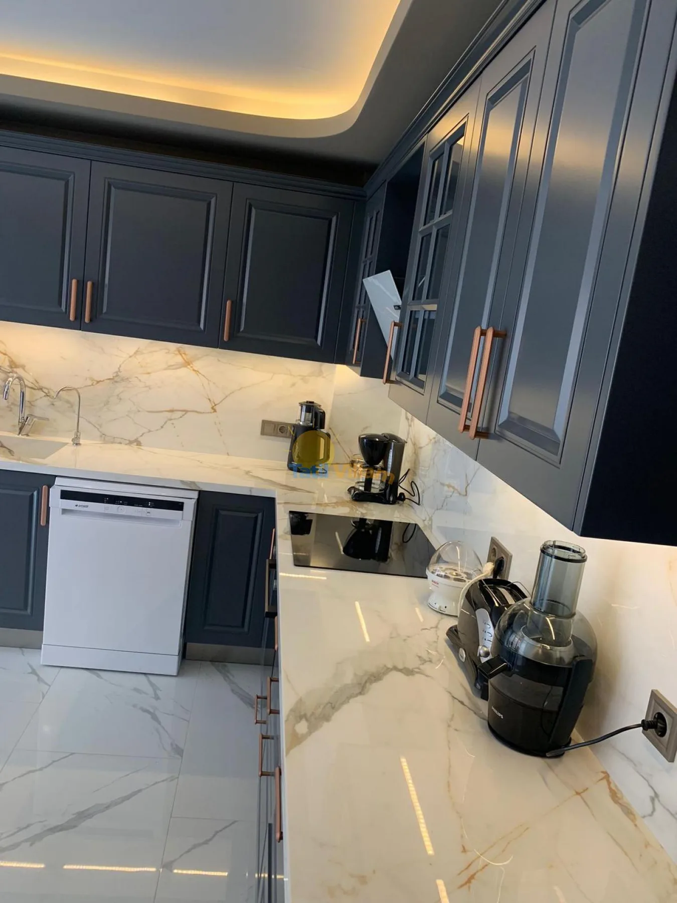 A modern kitchen with dark cabinets, a bright countertop, and small appliances.