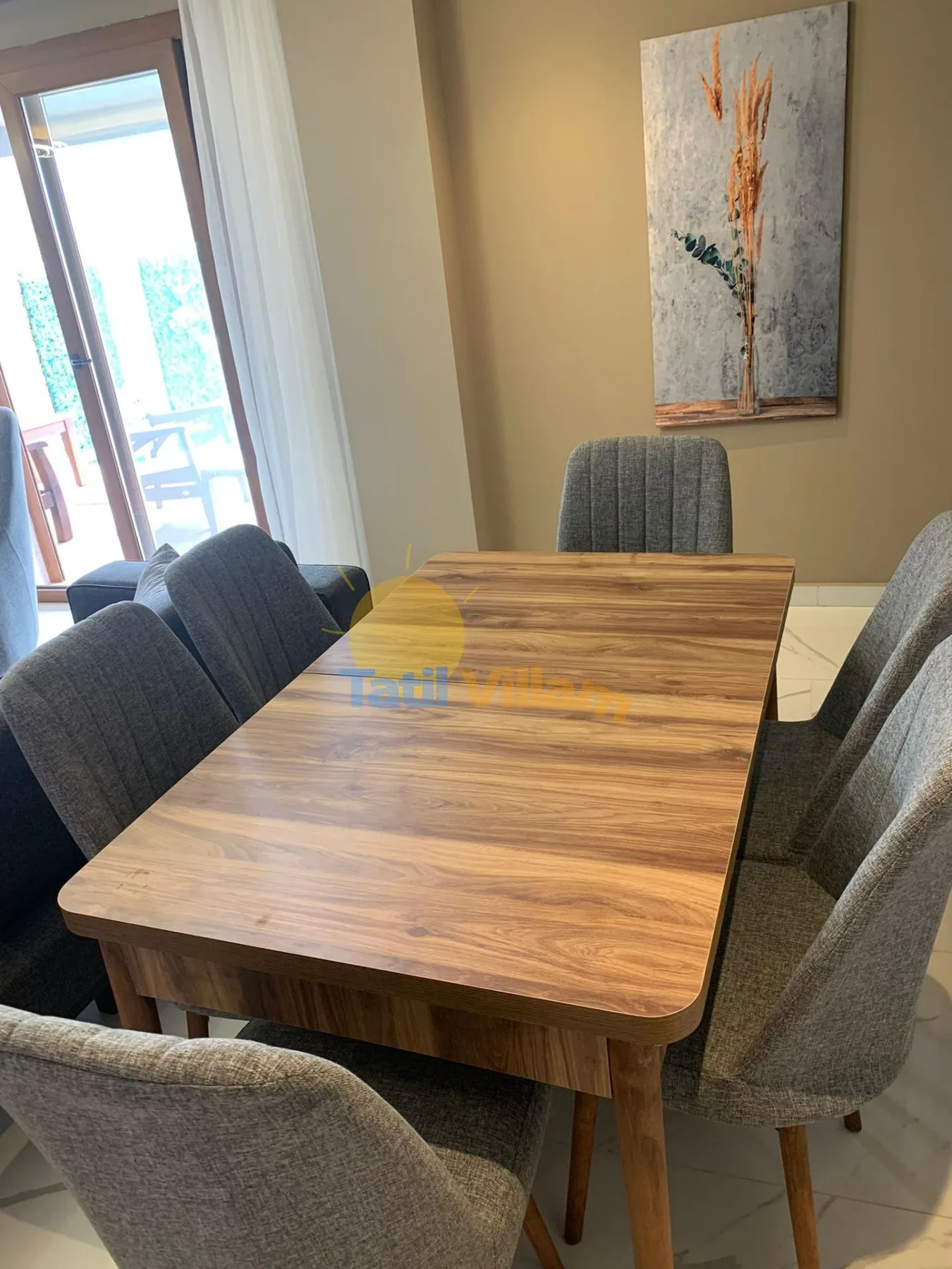 A dining area with a wooden table, upholstered seating, and wall art.
