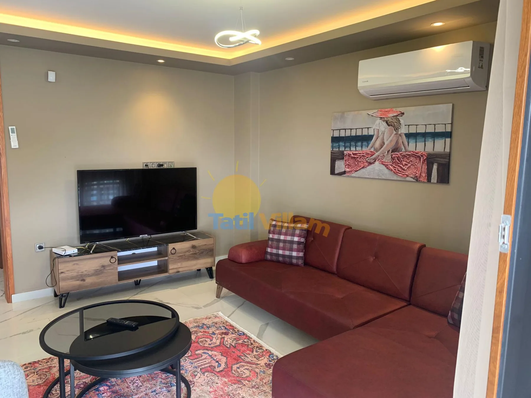 A living room with a television, a red sectional sofa, and a round coffee table.