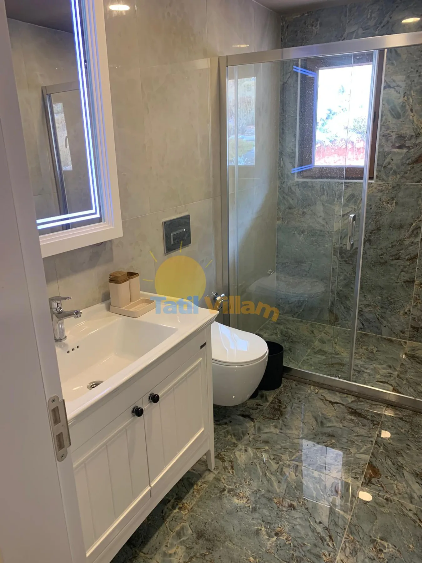 A bathroom with a sink vanity, toilet, and glass shower.