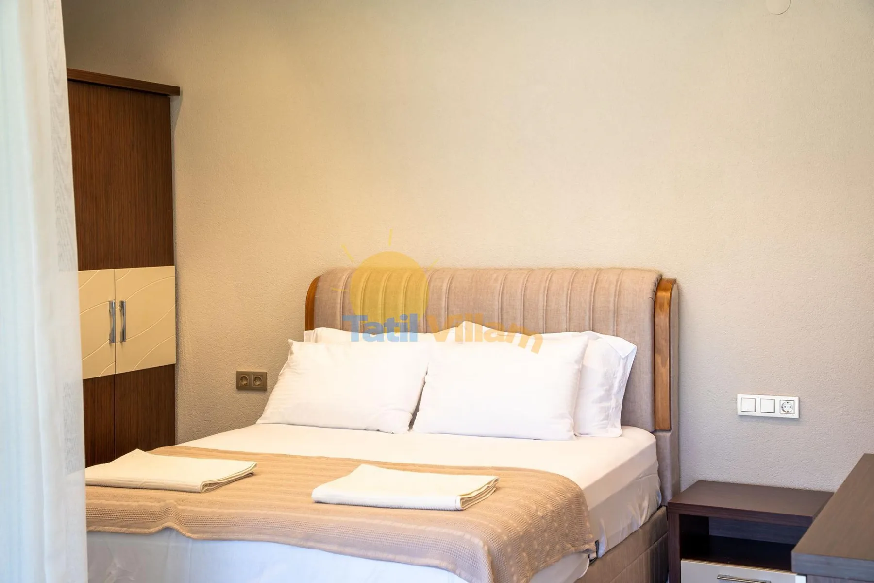 Un dormitorio con una cama bien hecha y toallas dobladas.