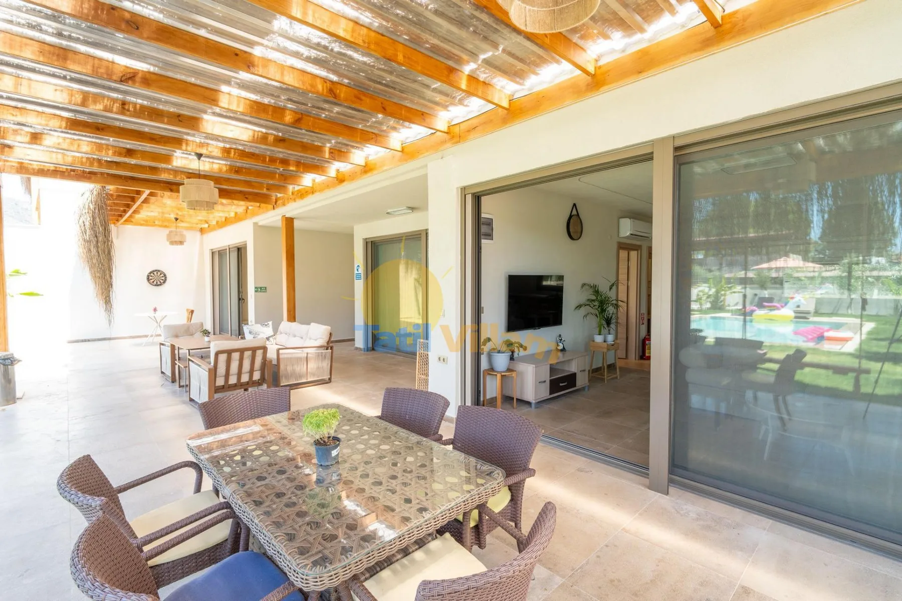 Un patio cubierto con mesa de comedor y asientos da a una sala interior.