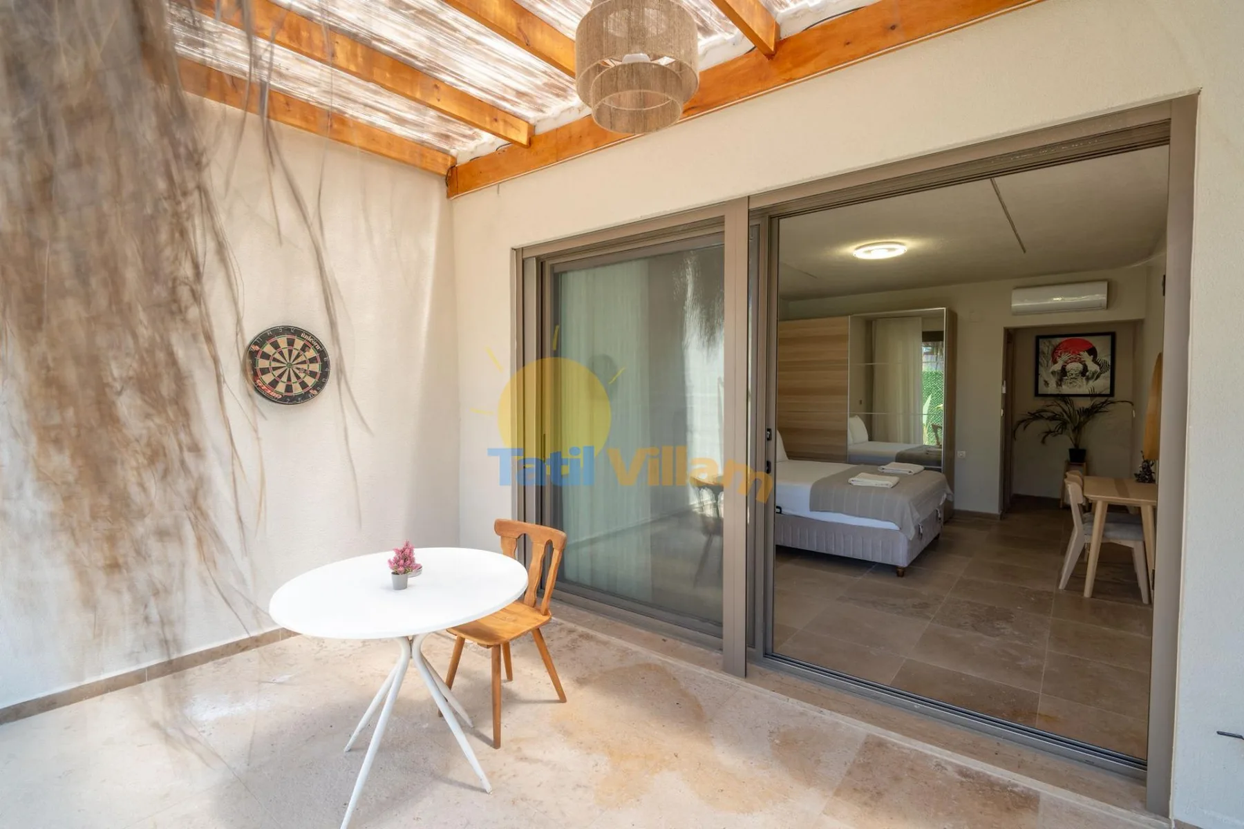 Una pequeña zona de estar al aire libre da a un dormitorio a través de puertas corredizas de vidrio.
